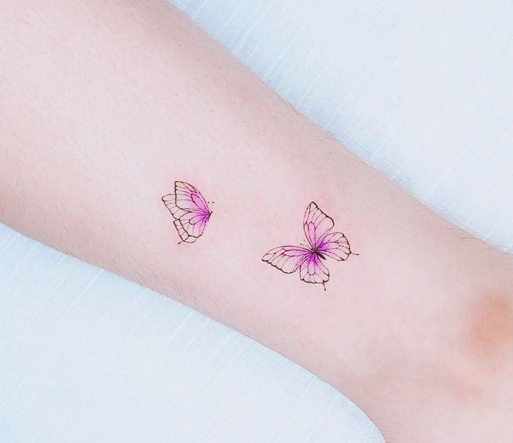 two pink butterflies on the left side of the arm, with one purple butterfly in the middle