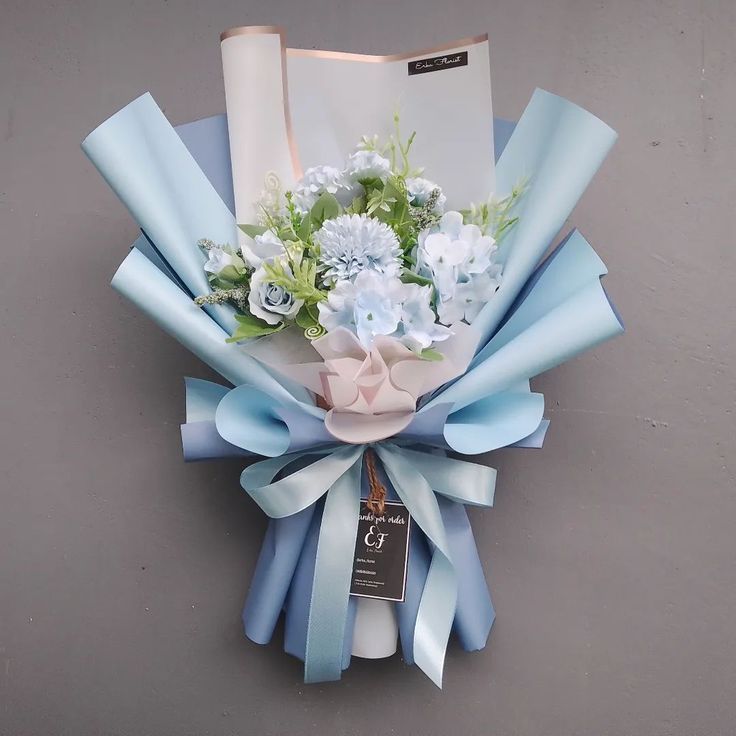 a bouquet of blue and white flowers is hanging on the wall next to a notepad