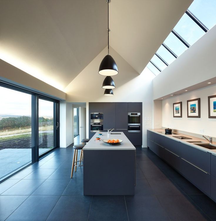 a modern kitchen with an island and skylights in the ceiling, along with large windows