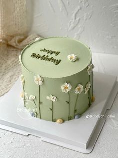 a green birthday cake sitting on top of a white plate with flowers and the words happy birthday written on it