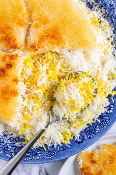 a blue plate topped with rice covered in cheese next to another plate filled with food