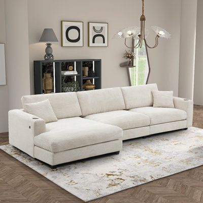 a large white couch sitting on top of a wooden floor next to a lamp shade