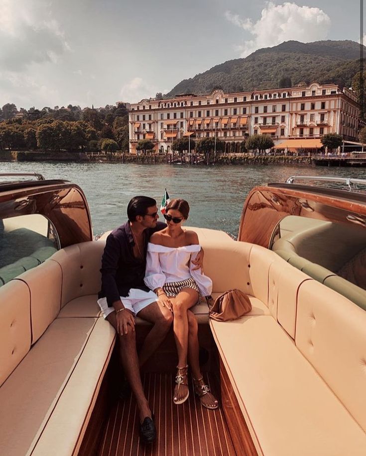 a man and woman sitting in the back of a boat on a body of water