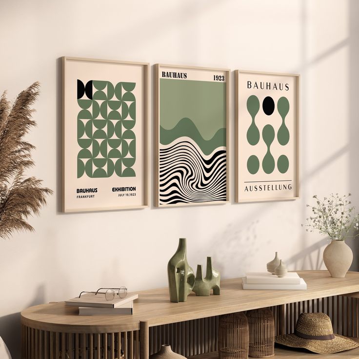 three posters on the wall above a table with vases and other items in front of it