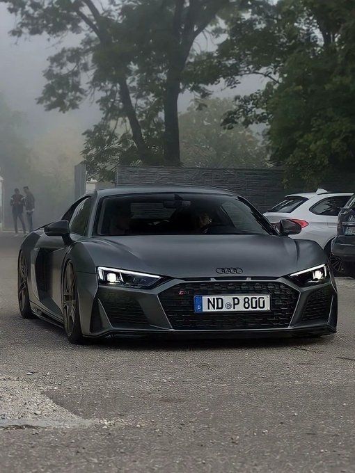 an audi sports car driving down the road in front of other cars on a foggy day