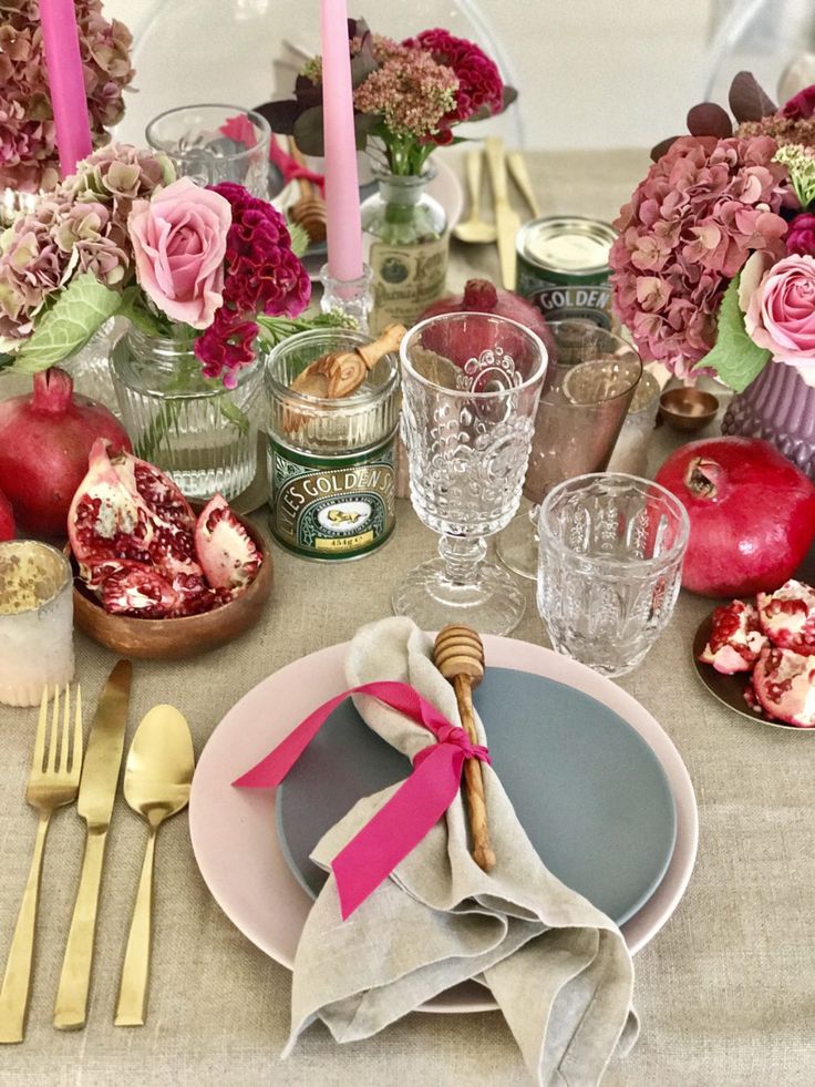 the table is set with pink flowers and silverware