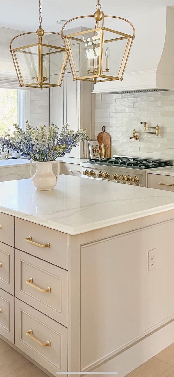 a white kitchen with gold accents and an island