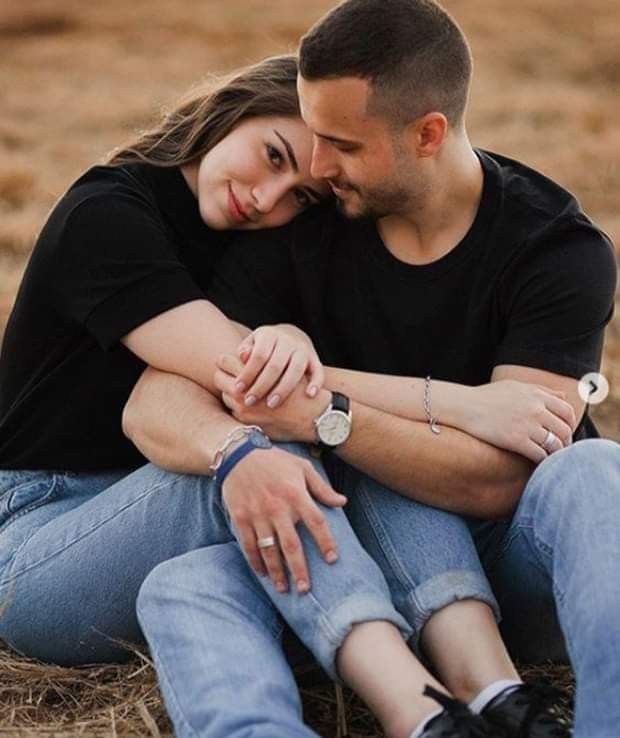 a man and woman sitting on the ground hugging each other with their arms around each other