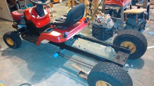 a red lawn mower parked in a garage next to other vehicles and people working on the machines