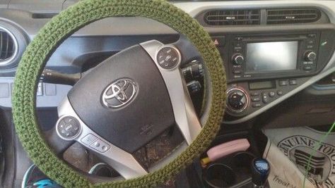 the steering wheel cover is knitted with green yarn and sits next to other items