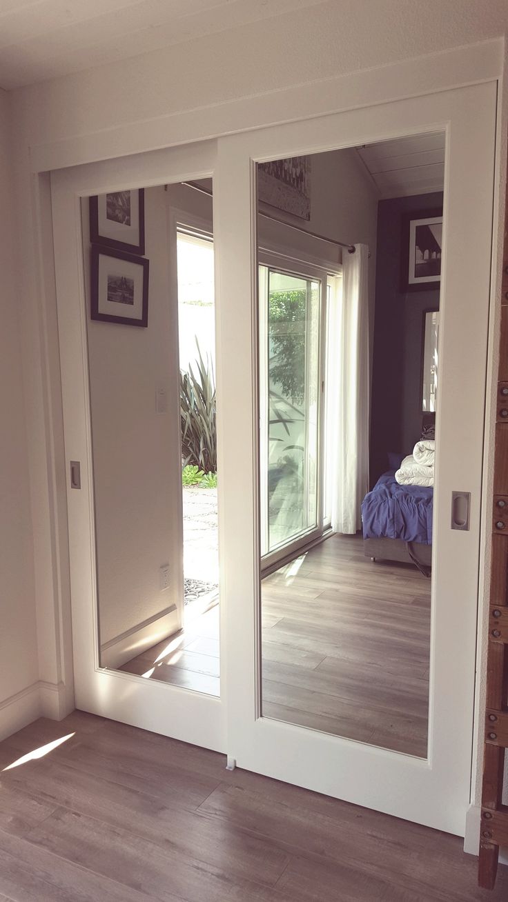 an empty room with mirrored doors and wood flooring in front of the sliding glass door