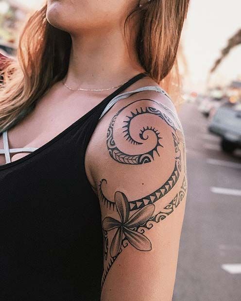 a woman with a tattoo on her arm standing in front of a street and looking off into the distance