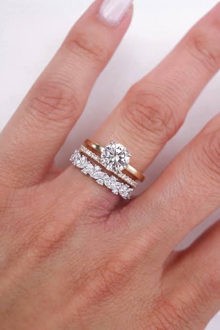 a woman's hand with two wedding rings on her left and the middle finger