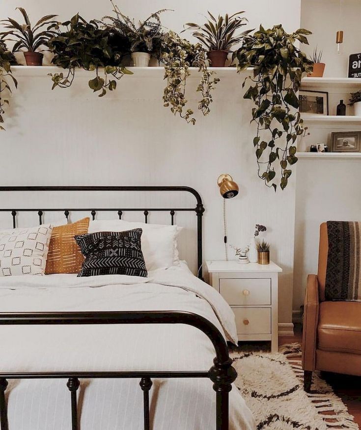 a bedroom with white walls and lots of plants hanging on the wall above the bed