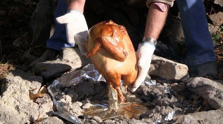 a man in white gloves washing a chicken on top of rocks and tinfoils