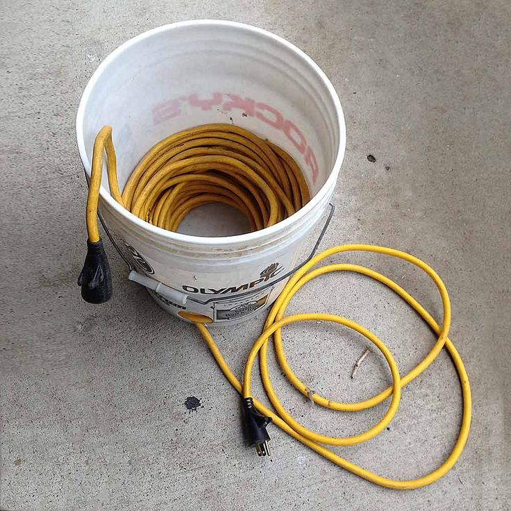 a bucket filled with yellow hoses sitting on top of a cement floor