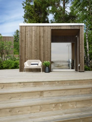 a wooden building with steps leading up to it and a white chair in the doorway