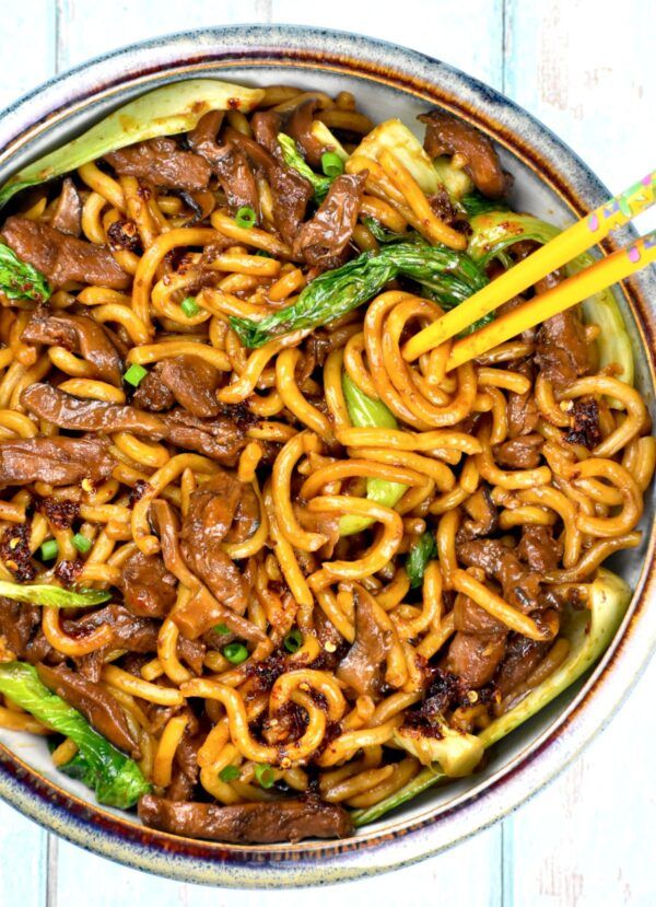 beef and noodles in a bowl with chopsticks