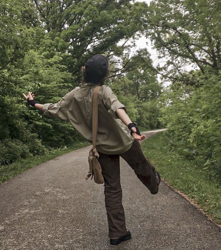 a woman is walking down the road with her arms outstretched in front of her back