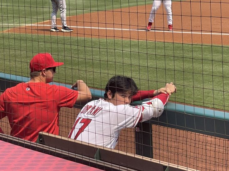 some baseball players are on the field and one is holding his arm over the fence