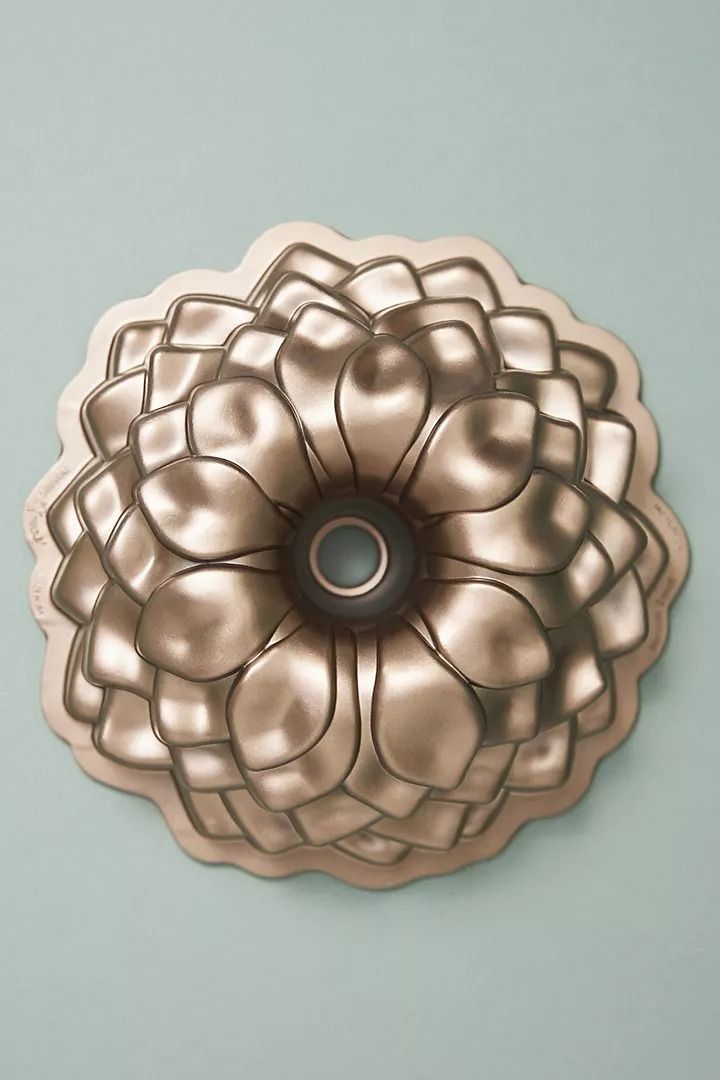 a decorative metal object on a blue wall with a black center piece in the shape of a flower