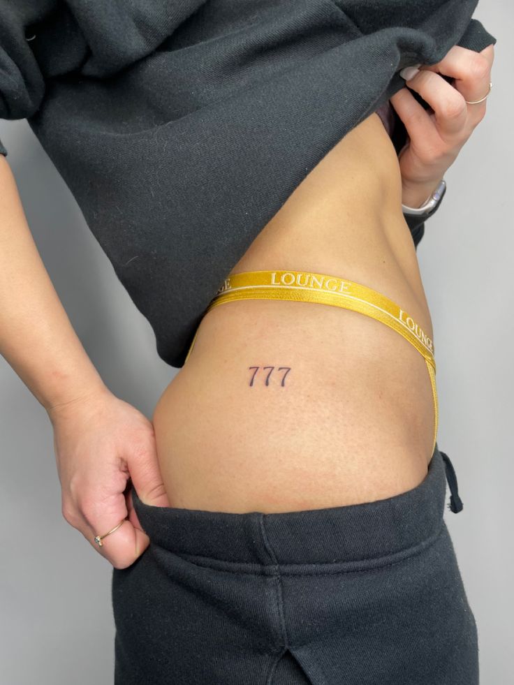 a woman's stomach with the word losing tattoo on her lower body and yellow tape around her waist