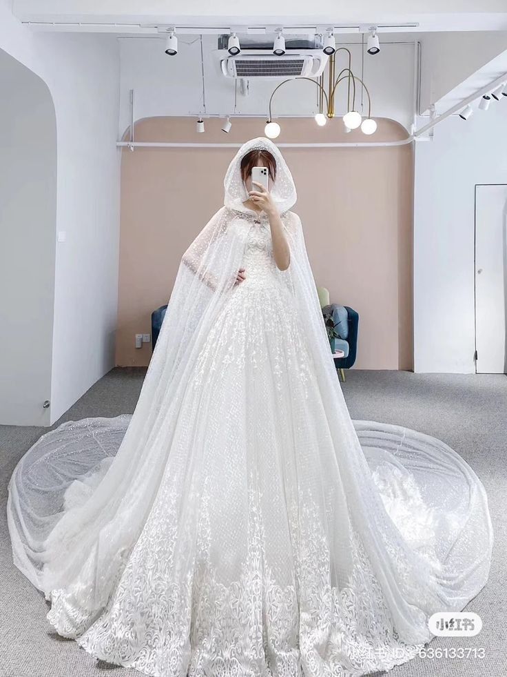 a woman in a wedding dress taking a selfie with her cell phone while wearing a veil