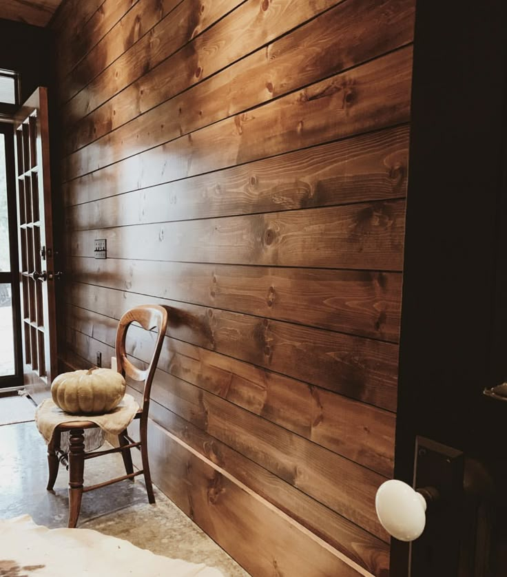 a chair sitting next to a wooden wall in a room with wood paneling on the walls