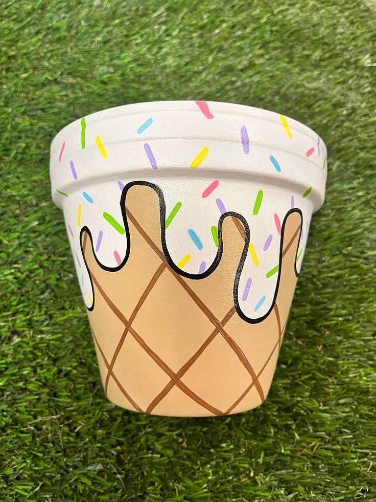 a paper cup with sprinkles and ice cream on it sitting in the grass