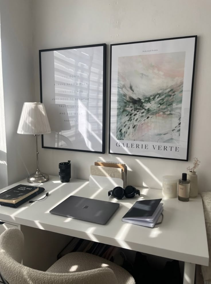 a white desk topped with a laptop computer next to a lamp and two pictures on the wall