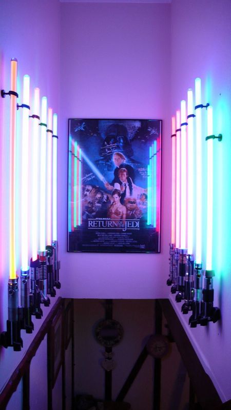 a movie poster hanging on the wall next to some neon lights in a room with a stairway leading up to it