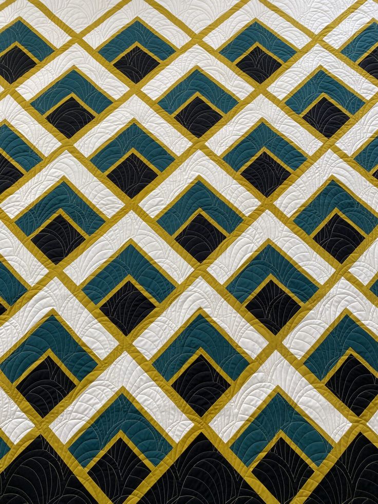 a close up of a quilt on a bed with blue and yellow squares in the middle