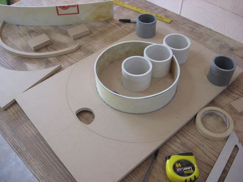 some cups are sitting on a table with construction supplies around them, including tape and scissors