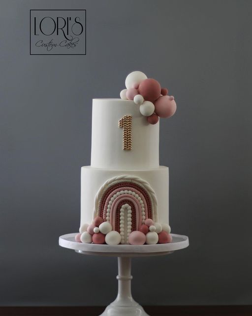 a three tiered cake with pink, white and gold decorations on the top layer