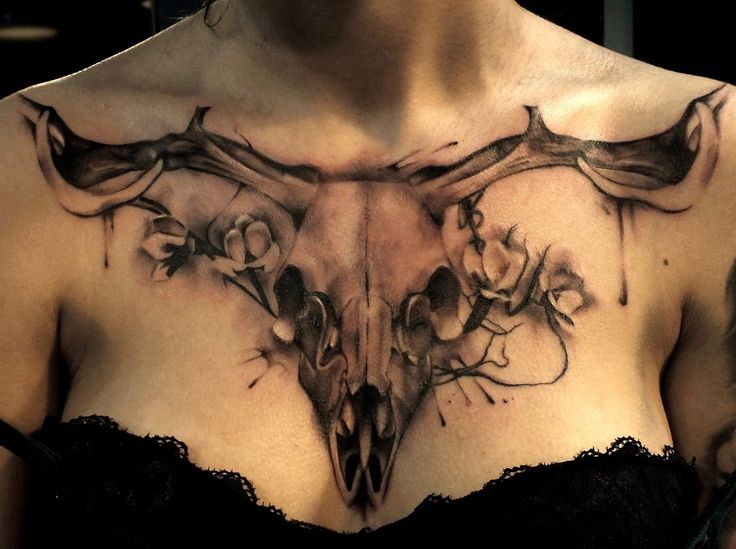 a woman's chest with an animal skull and flowers on it