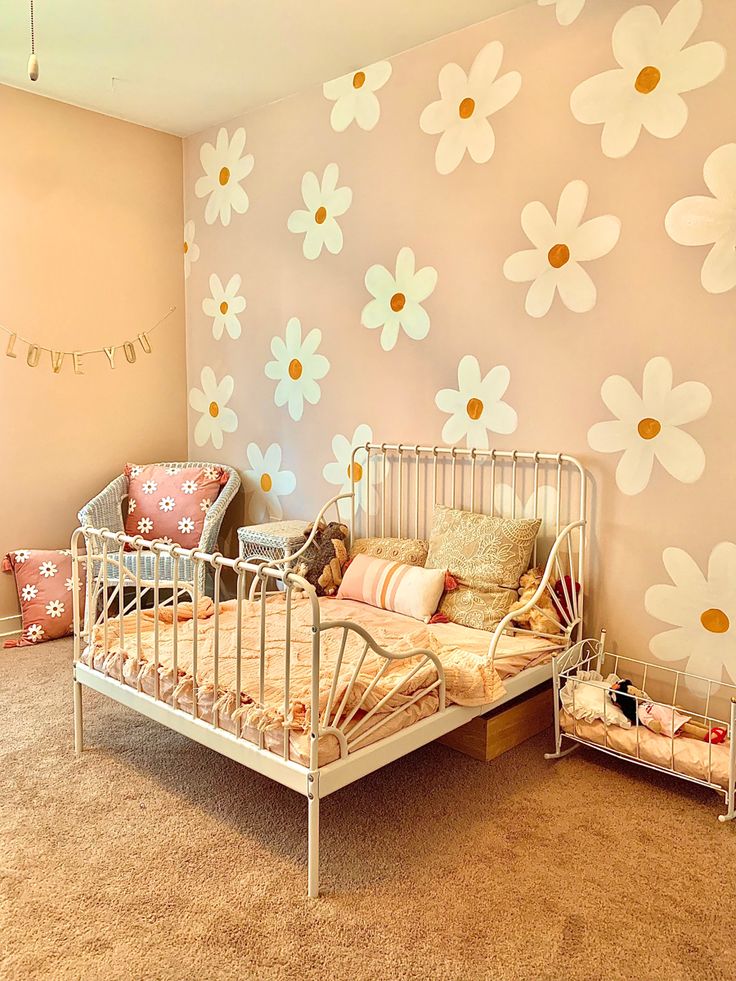 a bedroom decorated in pink and white with daisies on the wall