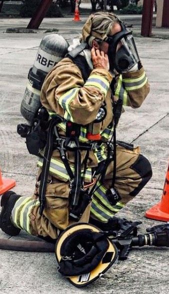 a fireman sitting on the ground talking on his cell phone