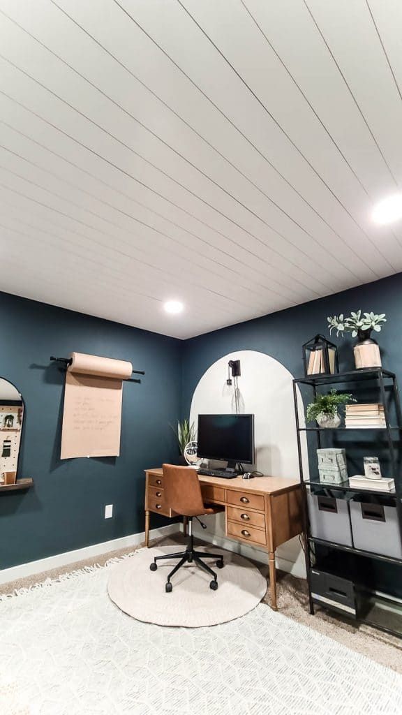 a home office with blue walls and white carpet