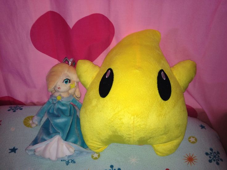 a yellow stuffed animal laying on top of a bed next to a princess figurine