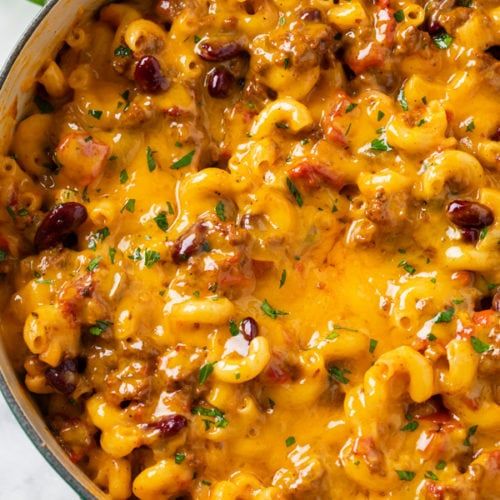 a skillet filled with macaroni and cheese covered in meat, beans and cheese