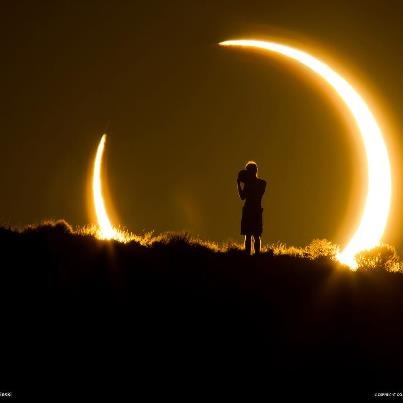 a person standing on top of a hill with the moon in the sky behind them