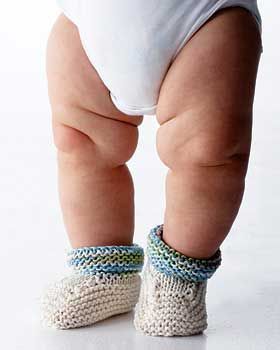 a baby in white diaper and socks standing up with his feet on the ground