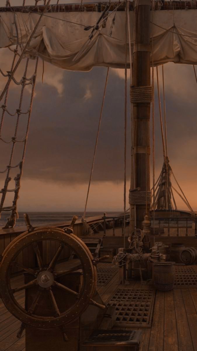 the deck of a large ship at dusk with clouds in the sky and water behind it