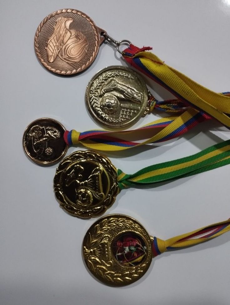 four medals with ribbons around them on a white surface, one is gold and the other is silver