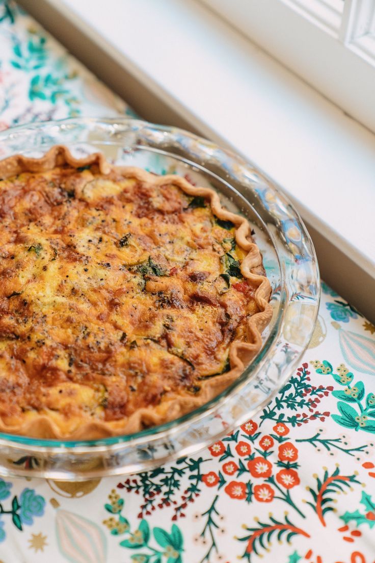 a quiche pie sitting on top of a table next to a window sill