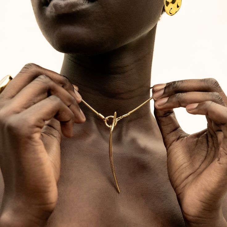 The Amali Lariat Necklace introduces a new curved quill silhouette for SOKO. This piece makes an impactful addition to your layers or makes for a beautiful, unique solo statement piece. In Swahili, Amali means hope. Handcrafted by artisans in Kenya with 24k gold plated brass using traditional casting techniques. Length: 20.07in (510mm)Brass Tube; 0.23in x 0.11in (6mm x 3mm)Toggle Dimension: 0.78in (20mm)Pendant Dimension: 2.36in x 0.15in (60mm x 4mm) Luxury Long Drop Brass Jewelry, Elegant Brass Toggle Necklace, Elegant Brass Lariat Necklace, Gold Lariat Necklace, Modern Gold Jewelry, Toggle Necklace, Dope Jewelry, Lariat Necklace, Selling Jewelry