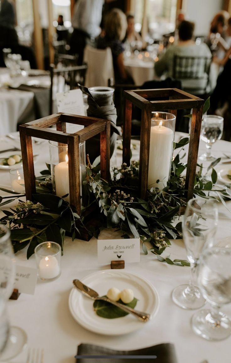 candles and greenery are placed on the table at this wedding reception in an elegant setting