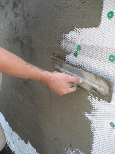 a man painting the side of a building with gray paint and green dots on it