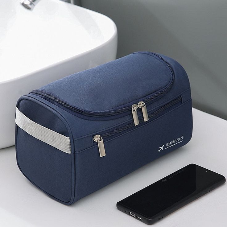 a blue toilet bag sitting on top of a white table next to a cell phone