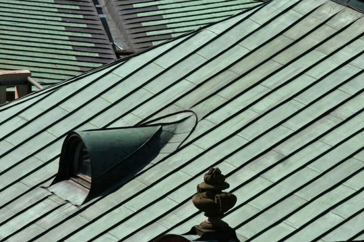 the roof of a building with a green metal shingled on it's side